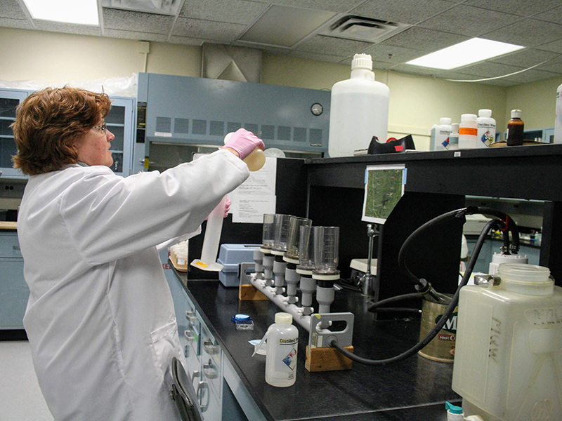 Woman working in lab coat in NRRI water chemistry lab. 