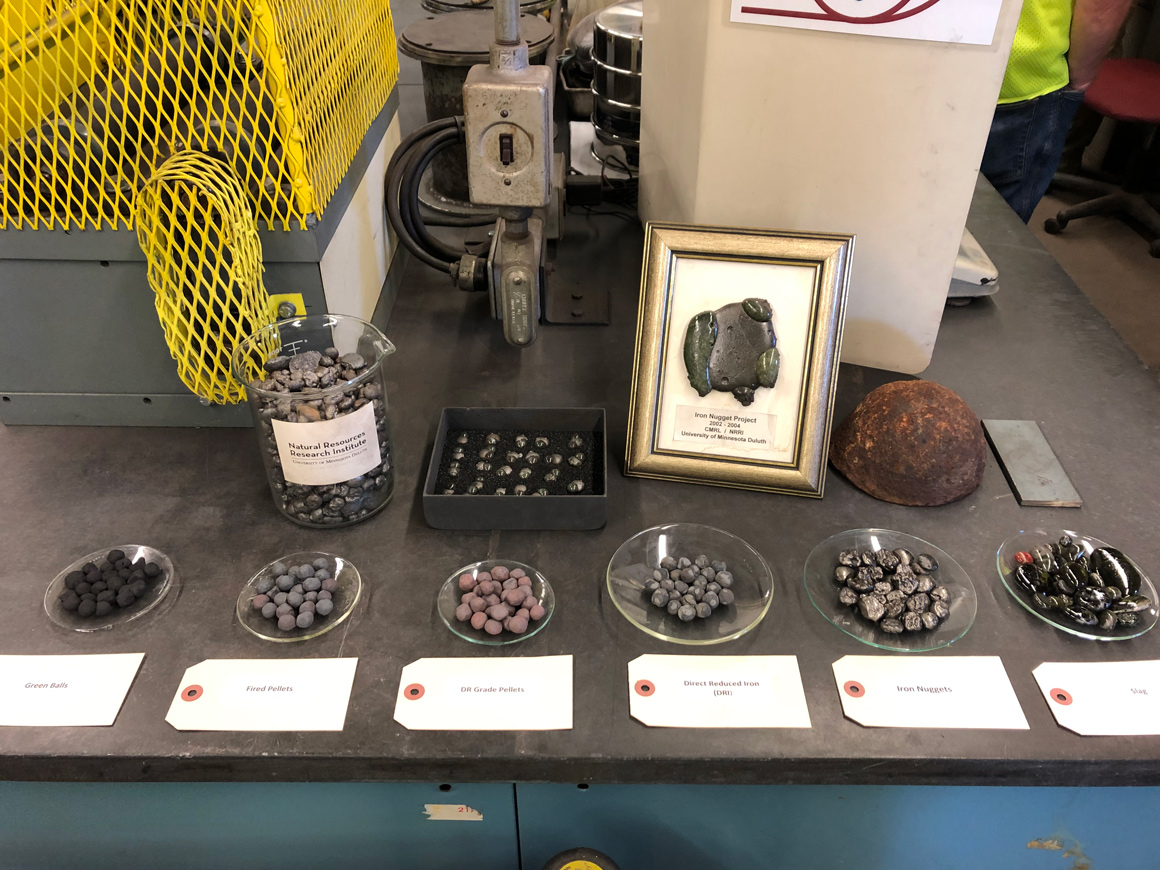 A display of iron types including jars and bowls with different types of iron pellets