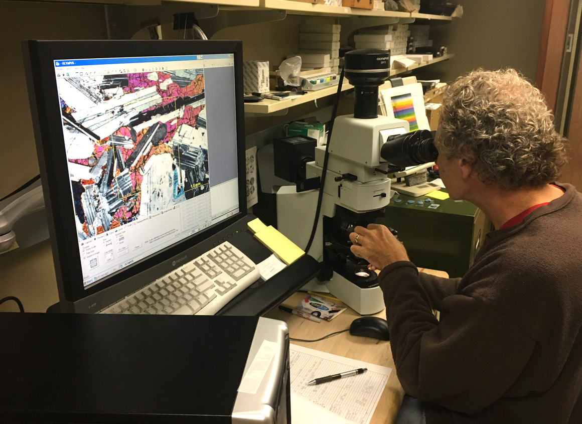 Researcher performs mineral characterization with microscope. 