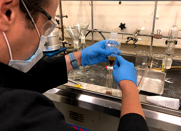 Researcher in the bio-chemistry la holding a vial in a fume hude