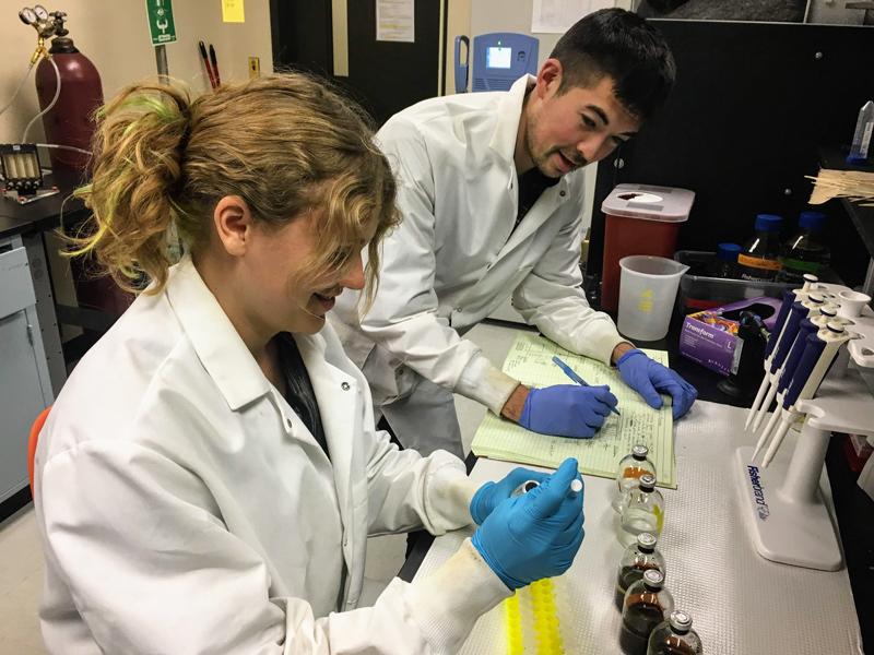 Researchers in white lab coats discuss results of chemical test. 