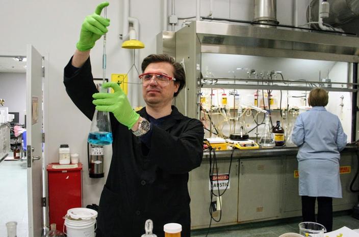 Researcher looks at beaker in the biomaterials chemistry lab.