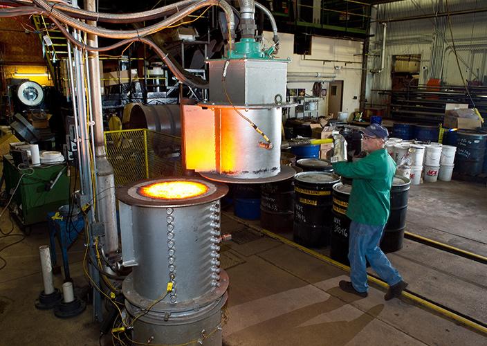 Man stands next to glowing industrial furnace