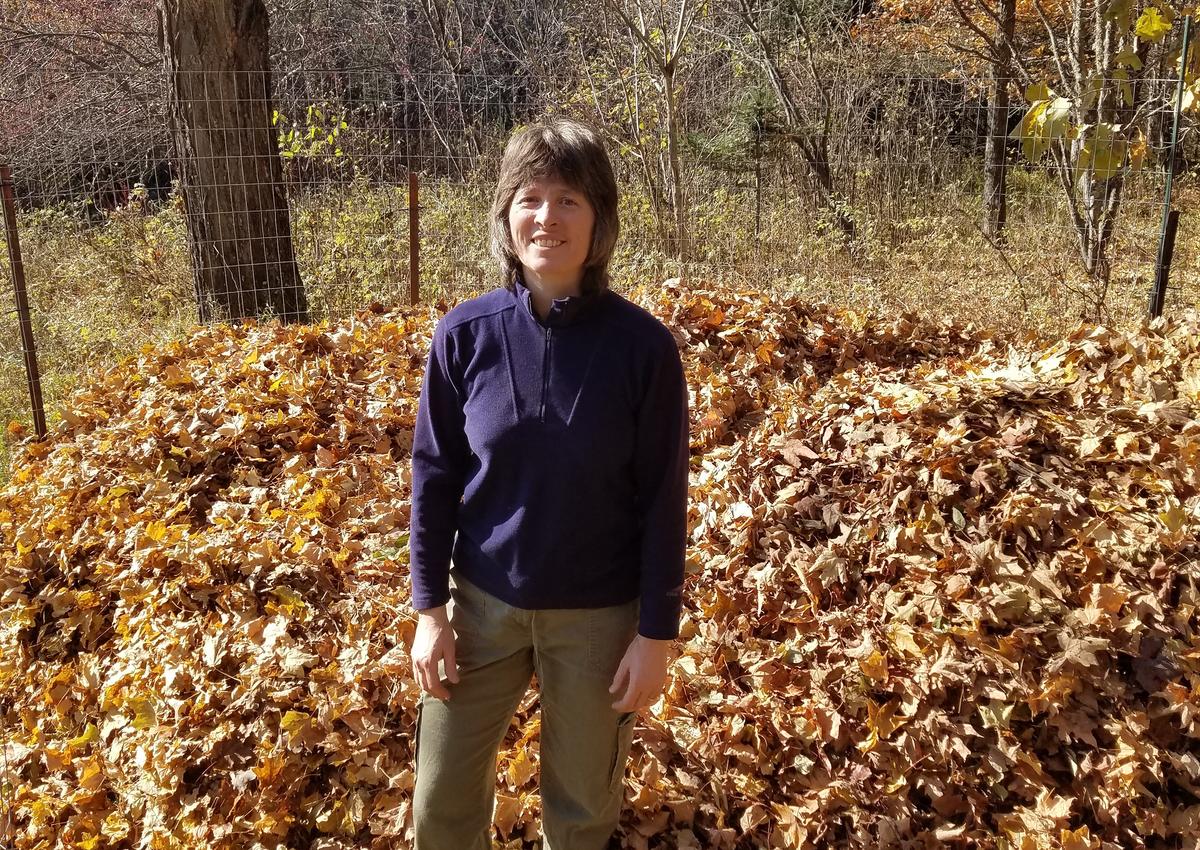 Valerie Brady stands among fall leaves outdoors
