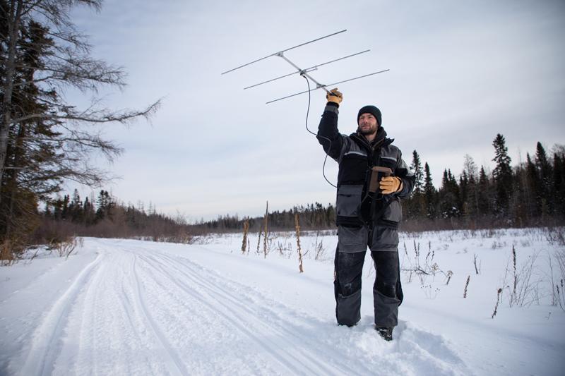 Profile Nate Wisenbeck standing in snow holding antenna. 