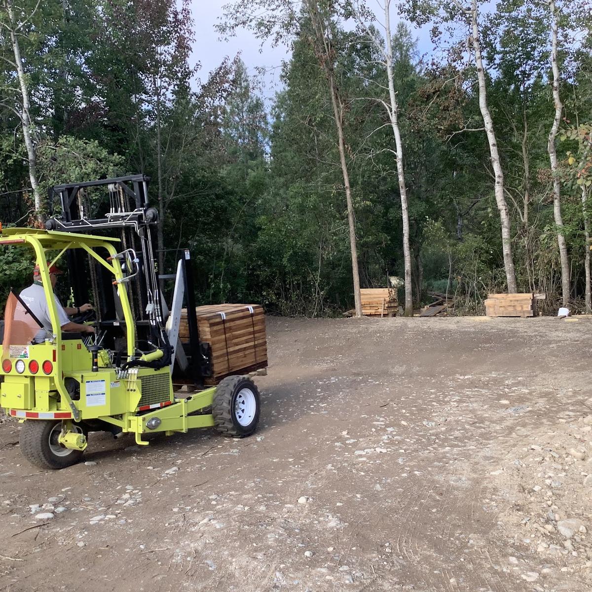 Small fork lift moving piles of lumber