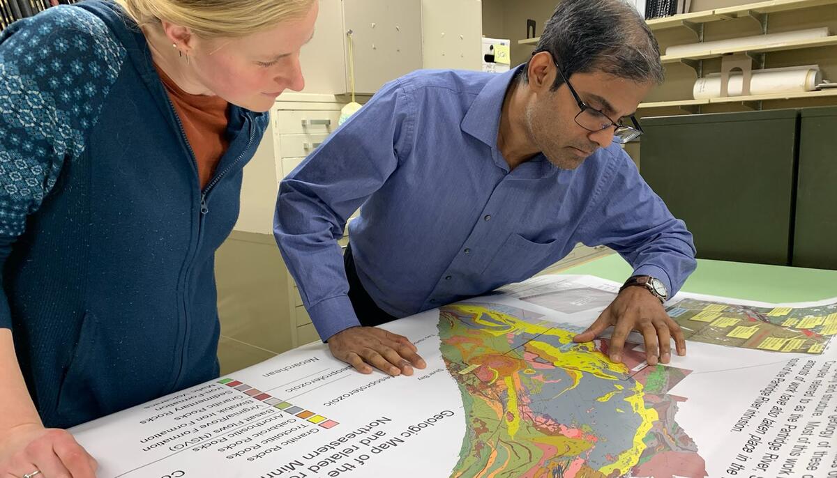 Two people look at a geology map showing the Minnesota Iron Range. 