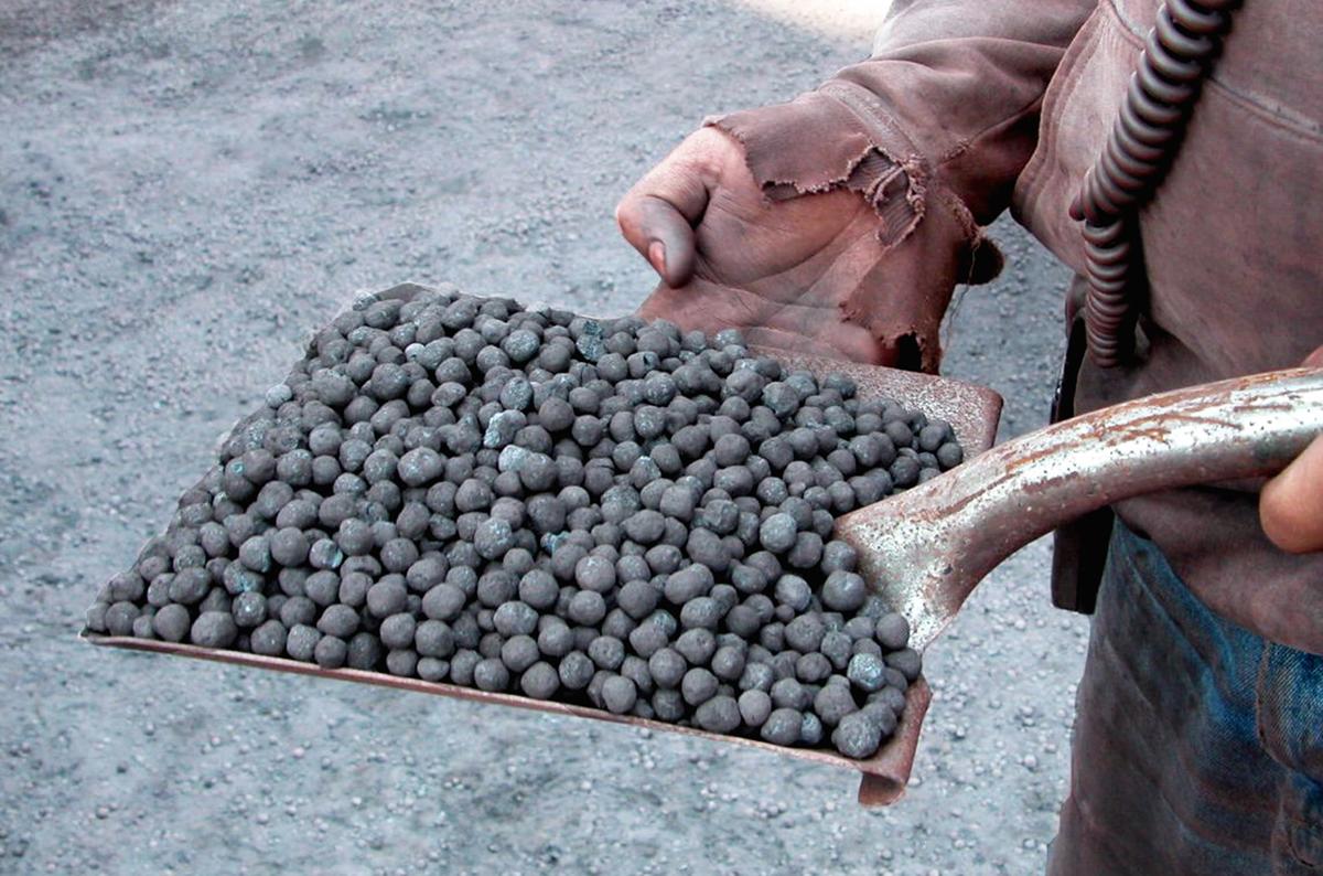 Shovel head filled with taconite pellets held by a man.