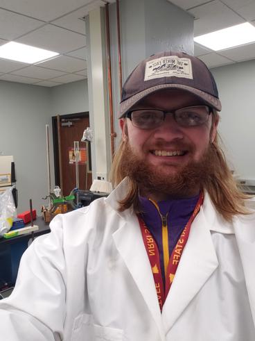 Brennan Pederson wearing baseball cap and lab coat