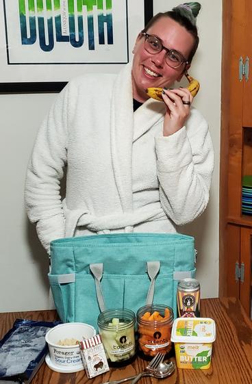 Woman poses next to a packed lunch, holding a banana  to her face like a telephone