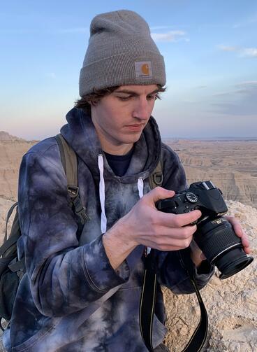 A man looks down at camera standing outdoors.