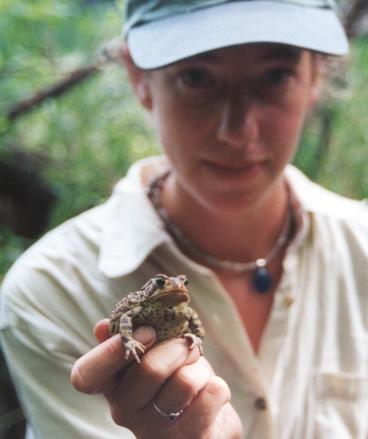 Woman in background holding up a frog to viewer